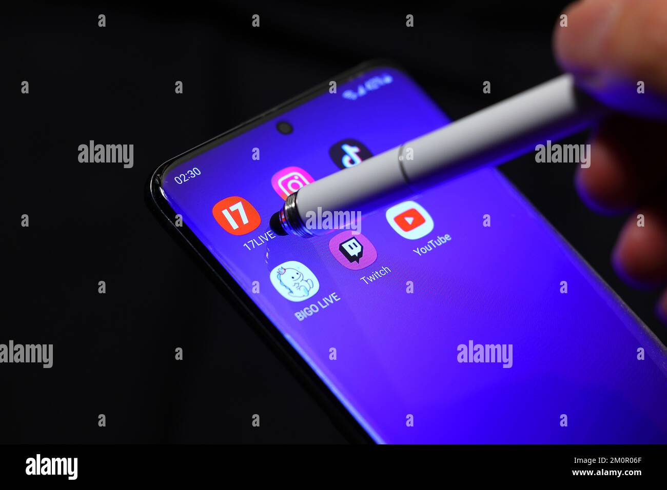 A stylus points to the 17Live livestreaming app on a smartphone with other streaming apps surrounding it. Stock Photo