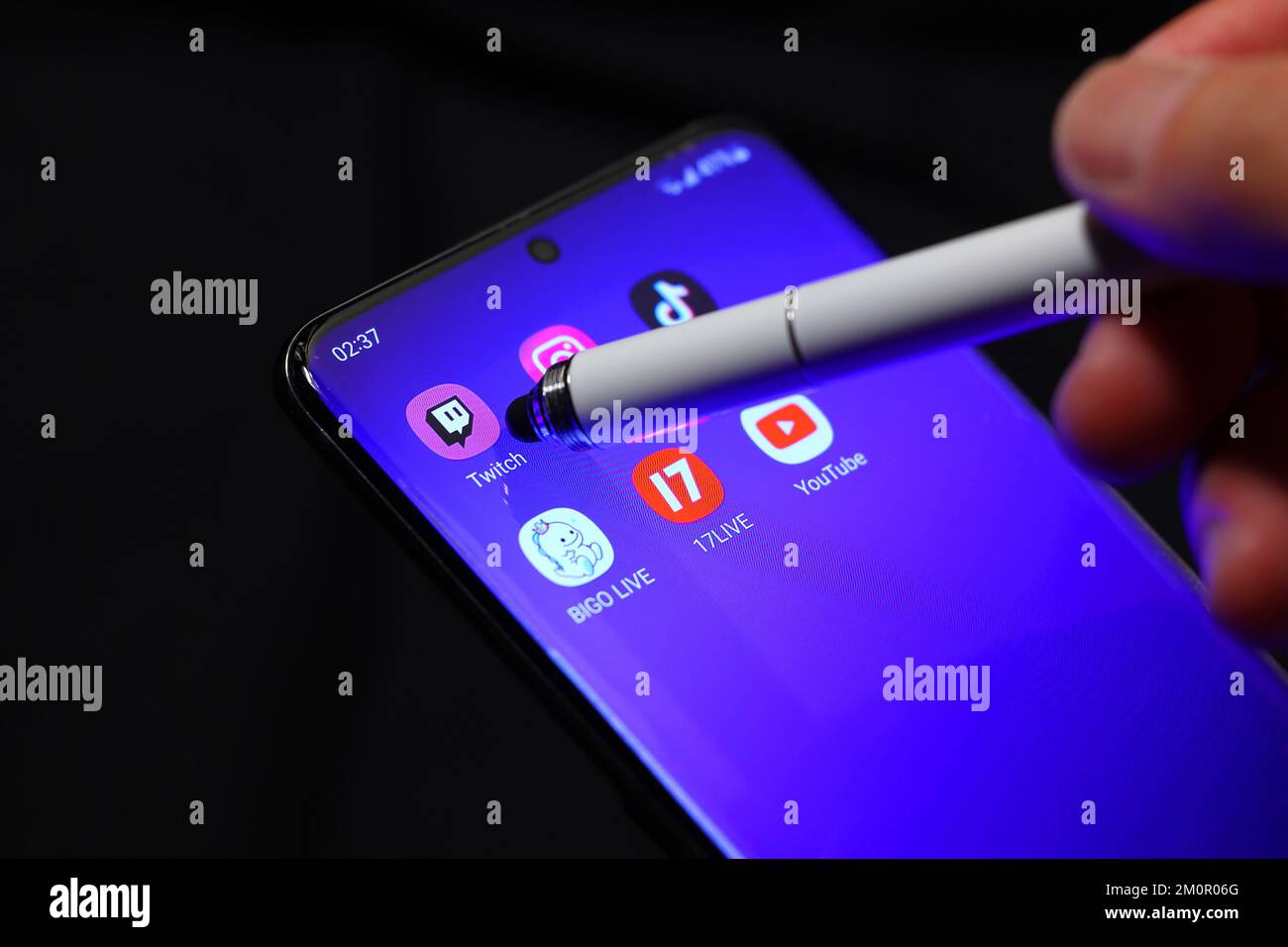 A stylus points to the Twitch tv livestreaming app on a smartphone with other streaming apps surrounding it. Stock Photo