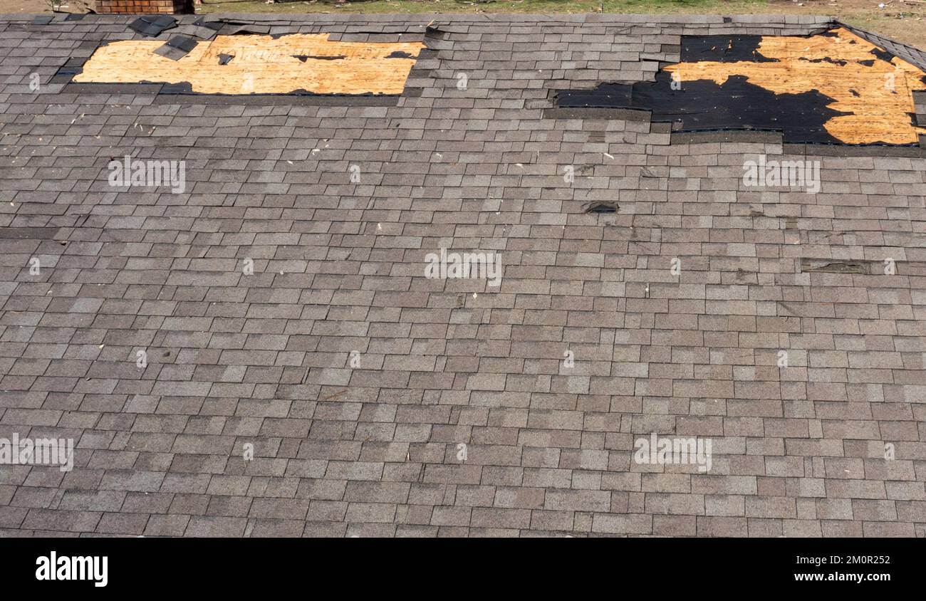 Roof with missing shingles, damaged by tornado during severe weather Stock Photo