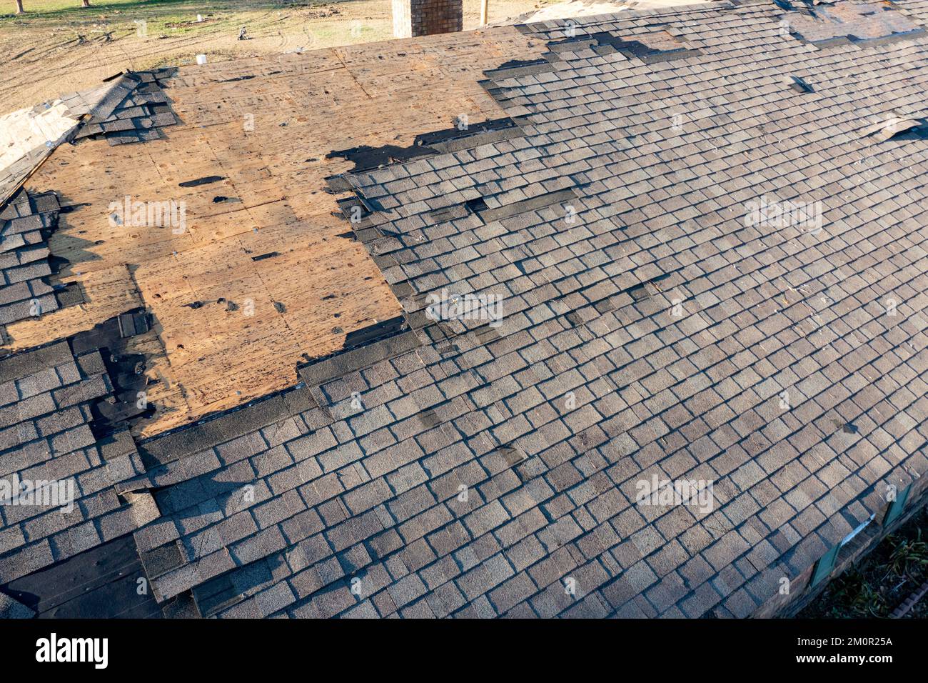 Roof and shingles damaged by tornado during severe weather Stock Photo