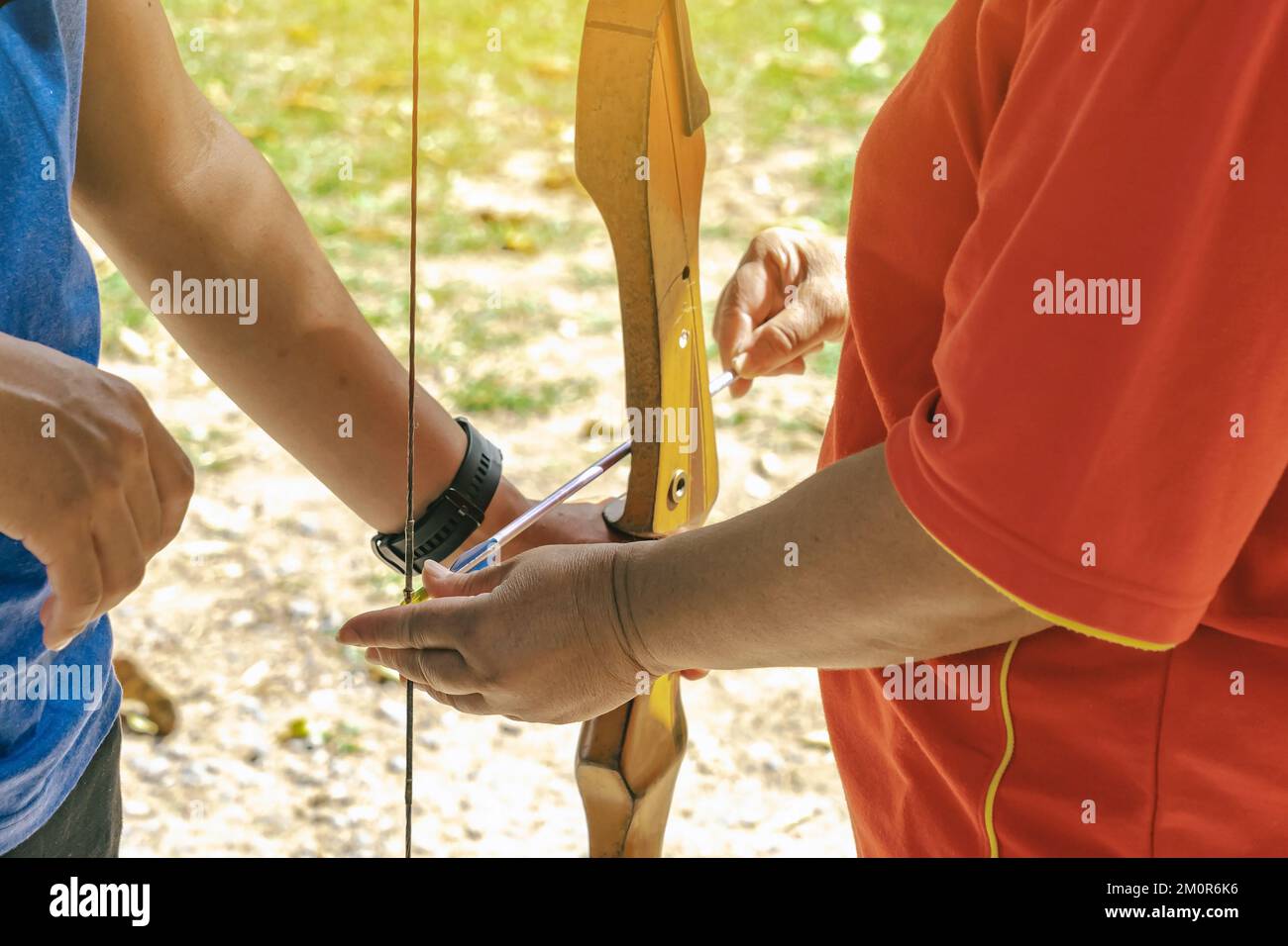 Female teacher teaches student to aim at goal. An archer teaching young