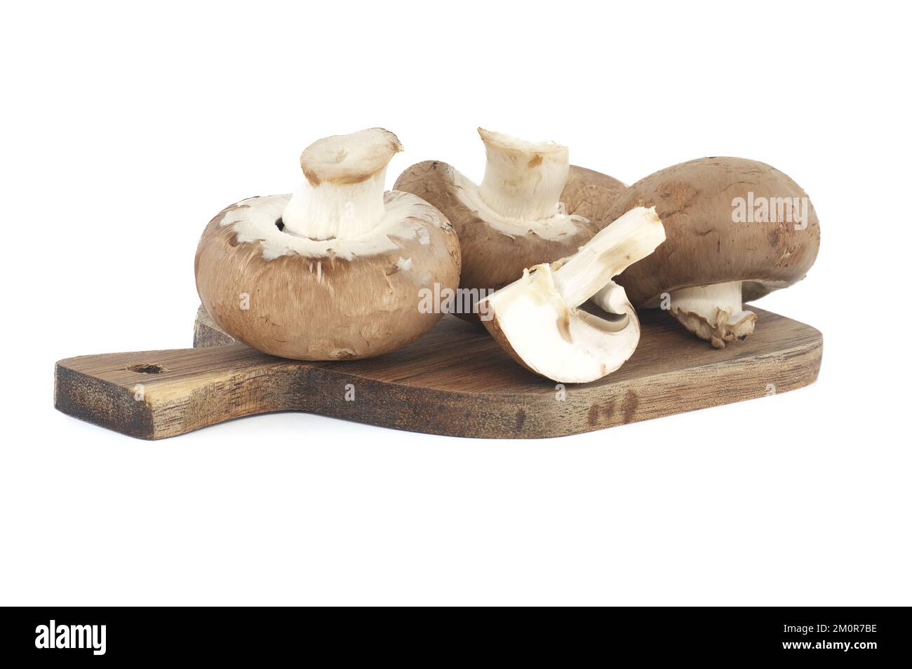 Fresh Baby Bella or Cremini whole mushrooms on wooden cutting board isolated on white background