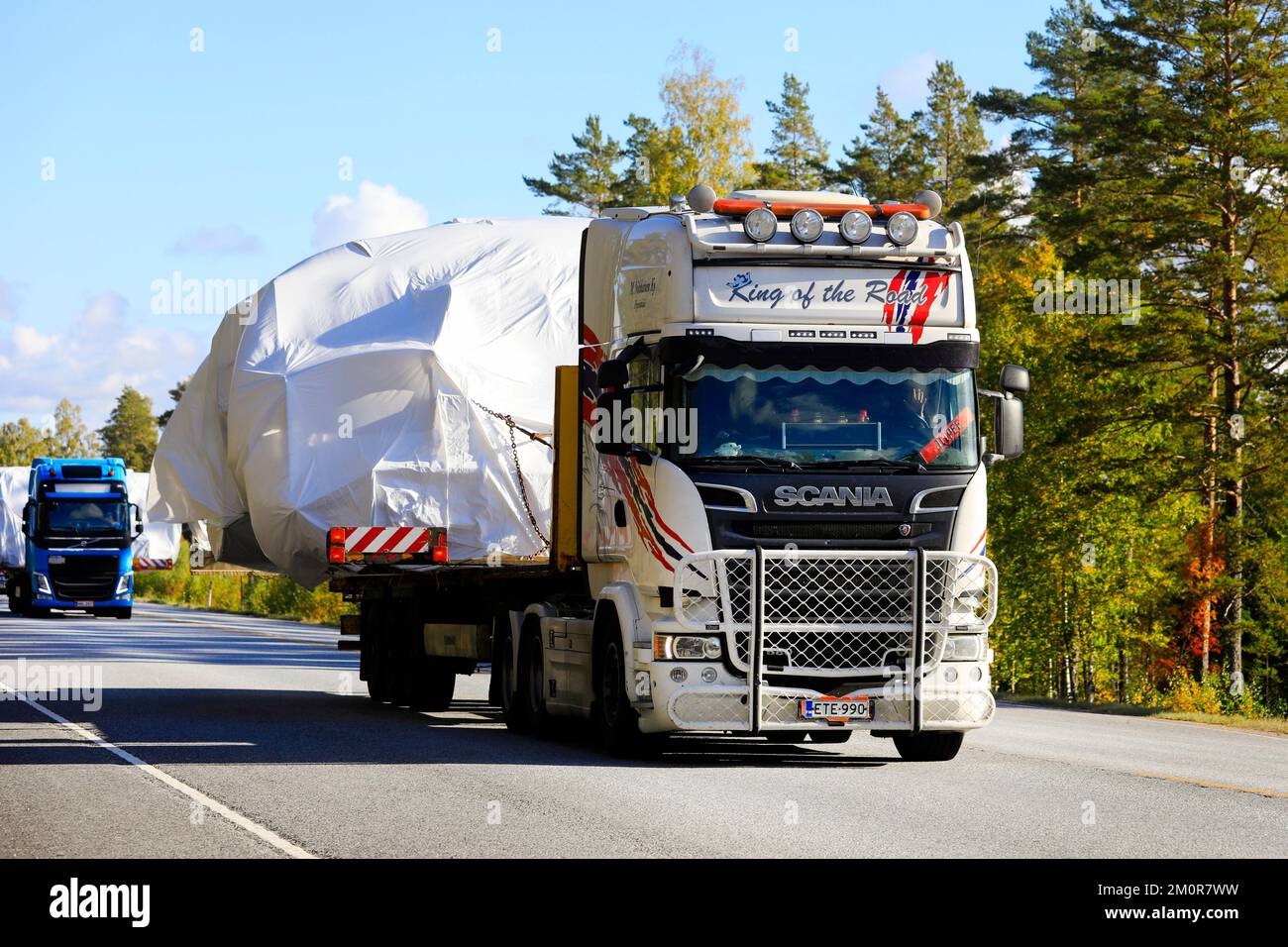 Two oversize load transporters, Scania R580 in the front, hauling tarpaulin covered wide loads towards Hanko port. Raasepori, Finland. Sept 23, 2022 Stock Photo