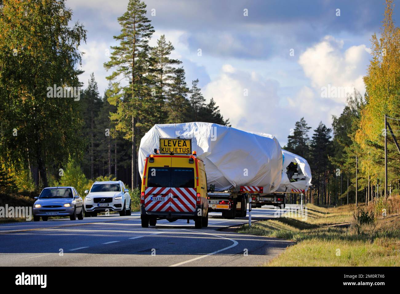 Cars from opposite direction give way as two oversize load transports assisted by pilot and escort vehicles proceed. Raasepori, Finland. Sept 23, 2022 Stock Photo