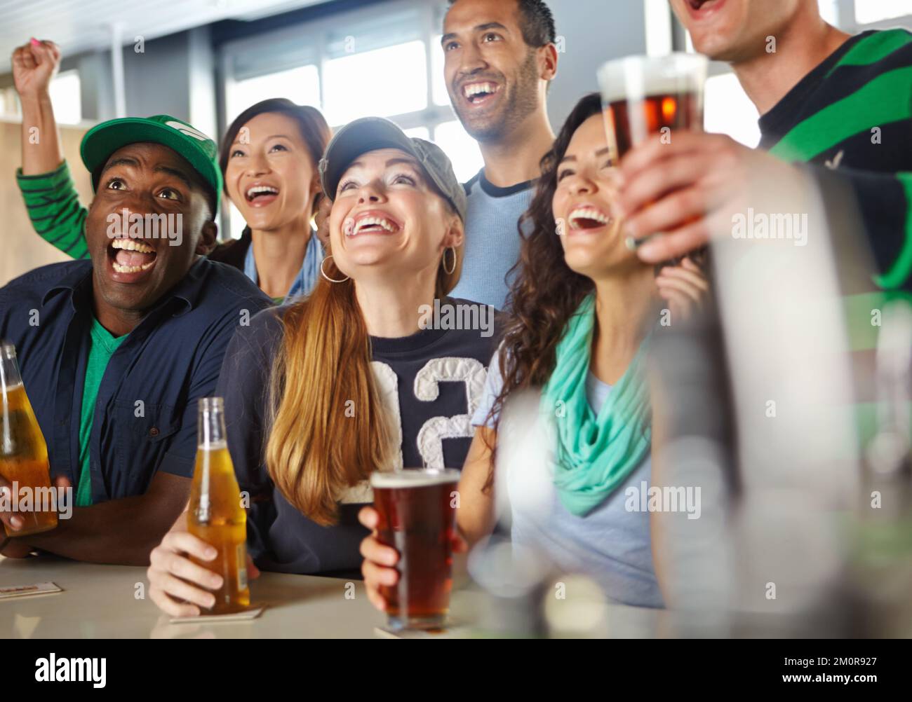 Come on. A group of friends cheering on their favourite sports team at the bar. Stock Photo