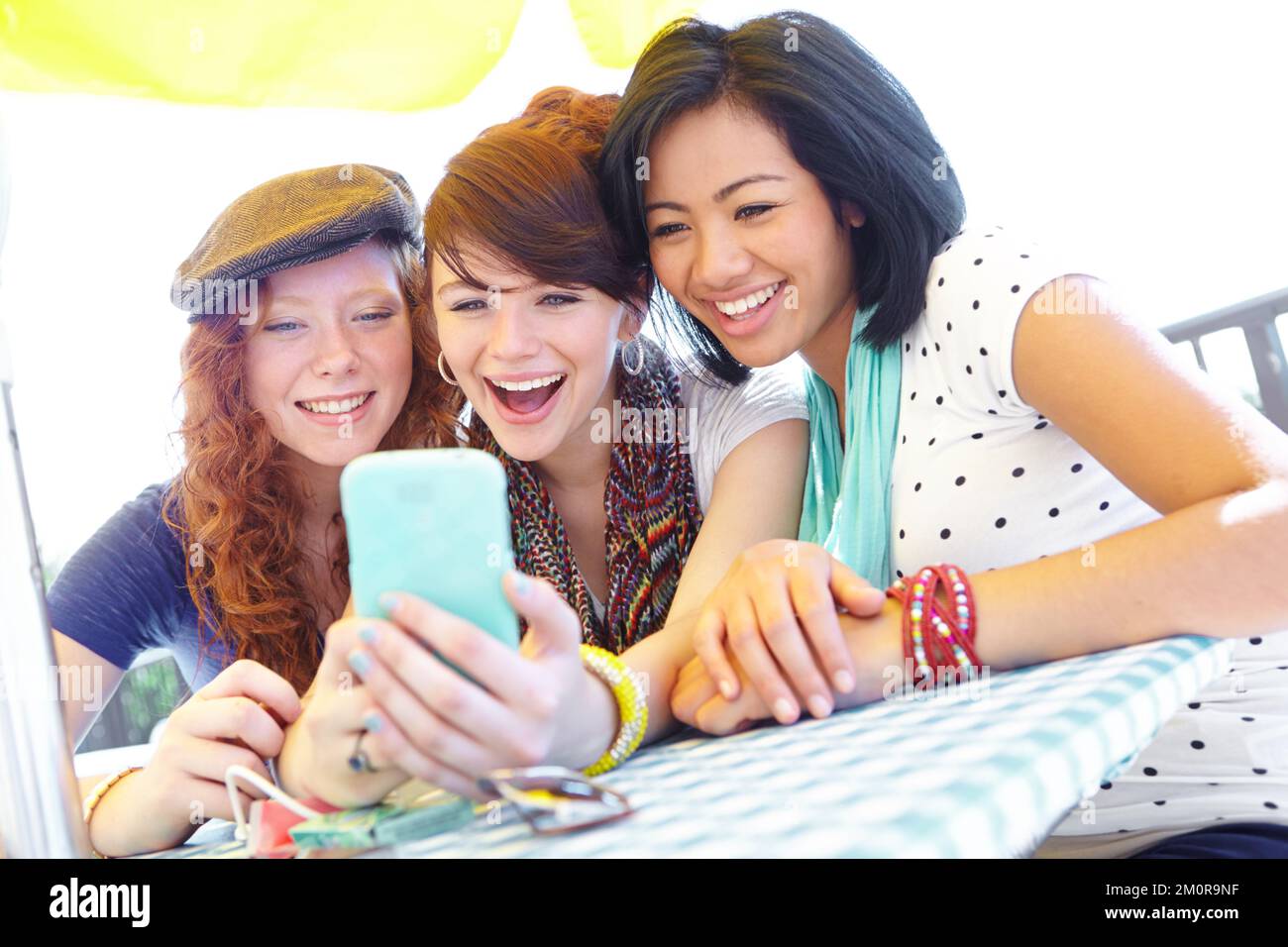 What a great photo. A group of adolescent girls laughing as they look at something on a smartphone screen. Stock Photo