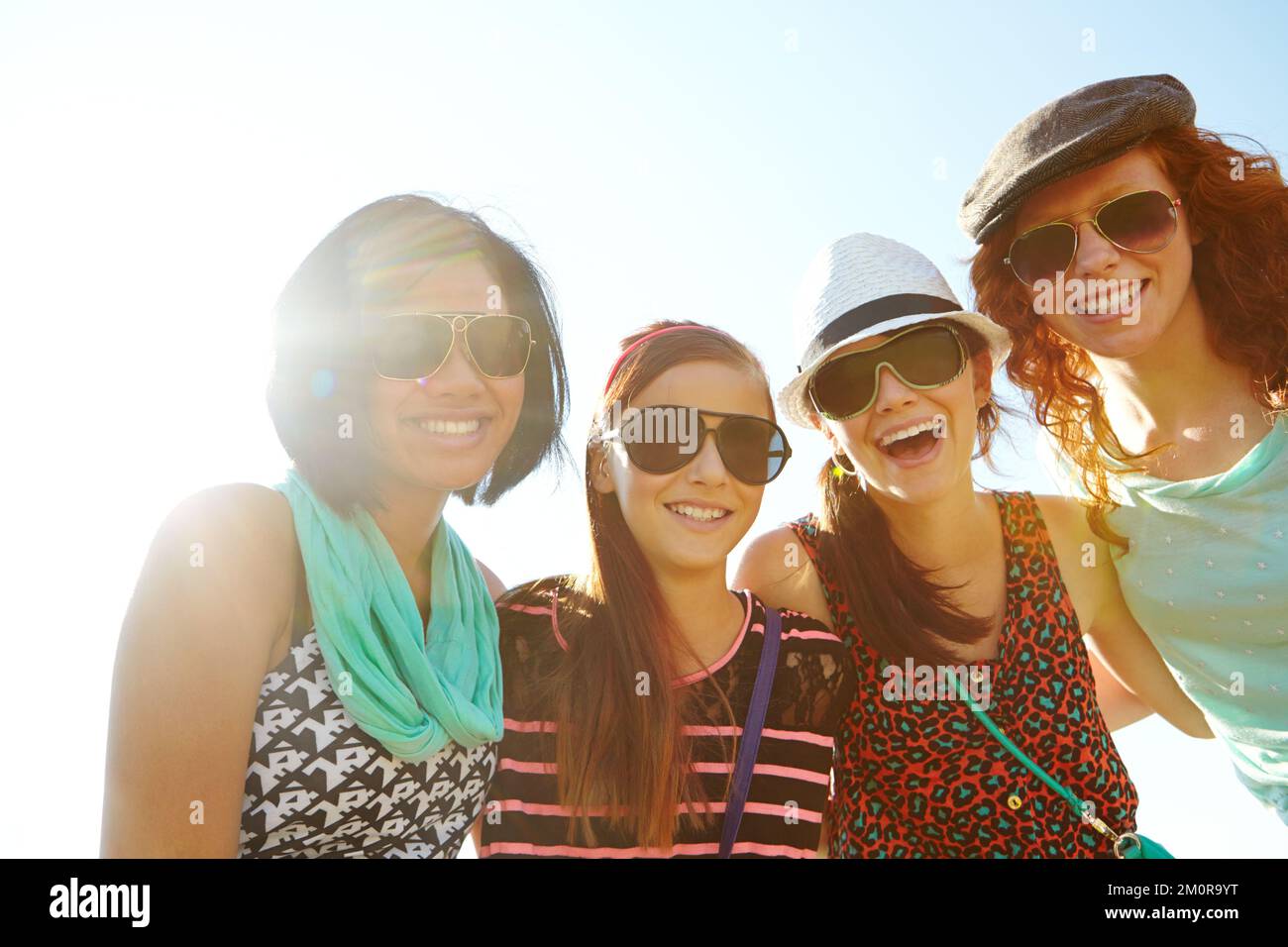 True friends are always by your side. A group of four teenage girls smiling with their arms around each others shoulders. Stock Photo