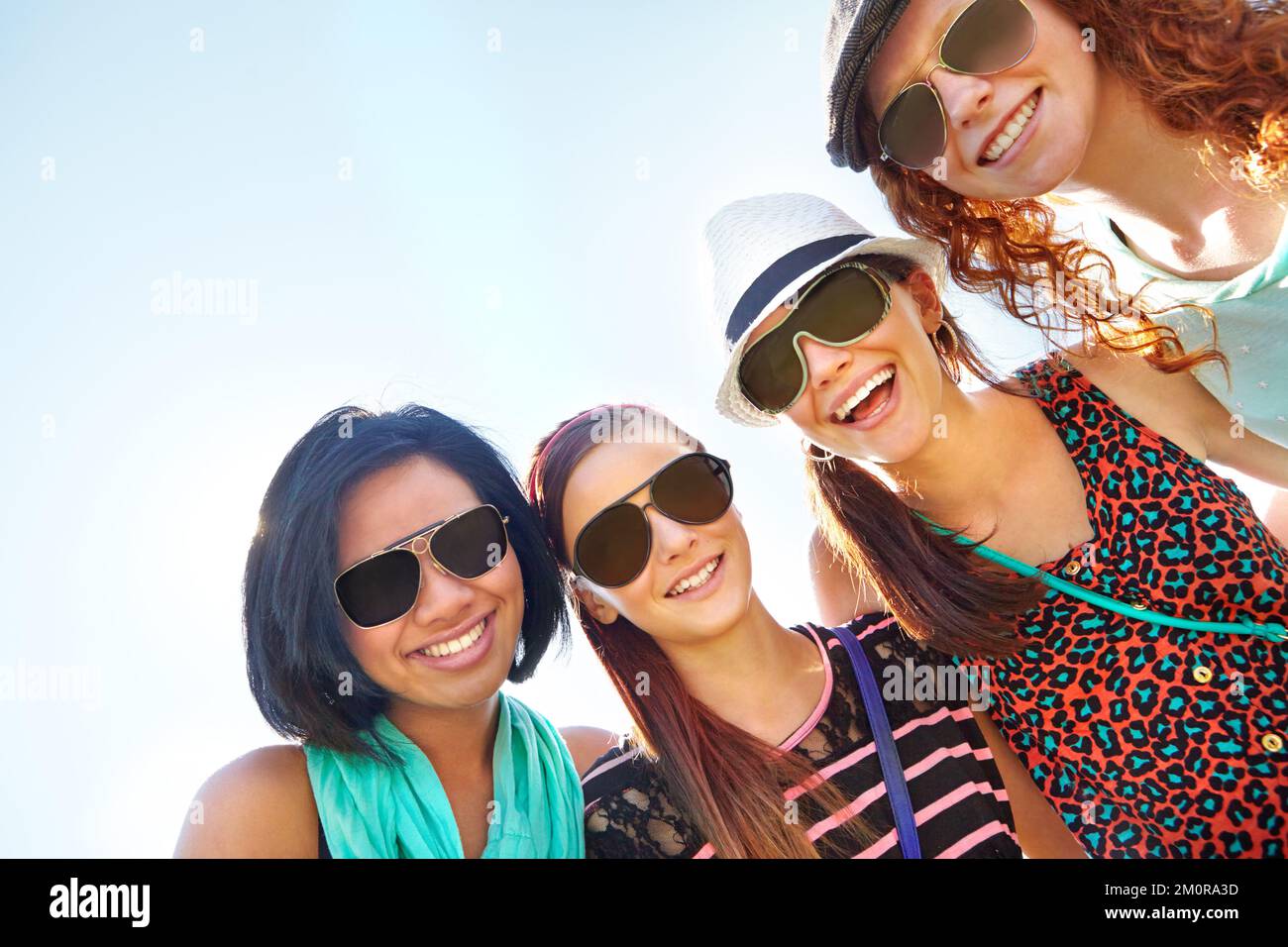 Life is nothing without friendship. A group of four teenage girls smiling with their arms around each others shoulders. Stock Photo