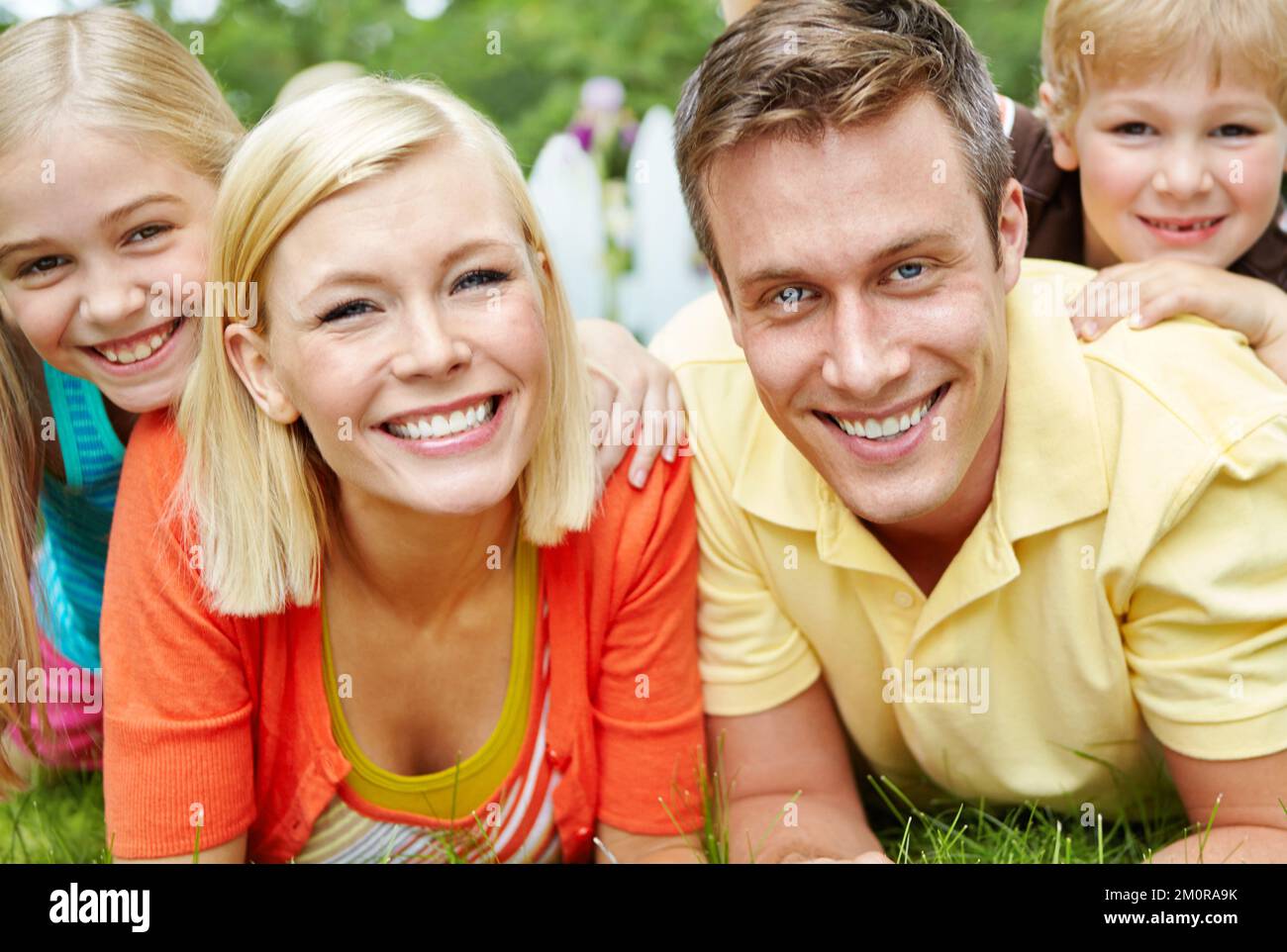 Theyre such a happy family. Happy young family lying together on the grass at home. Stock Photo