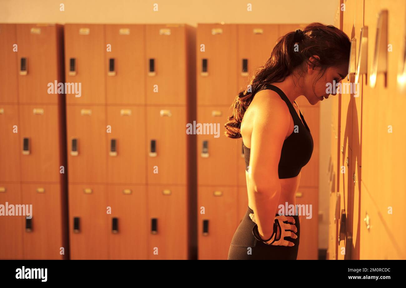 Tired woman  standing in the locker room after a workout at the gym. Stock Photo