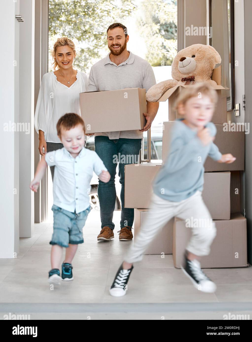 Happy family moving into new house. Excited children running into their new house. Family carrying boxes, moving into their house. Happy caucasian Stock Photo