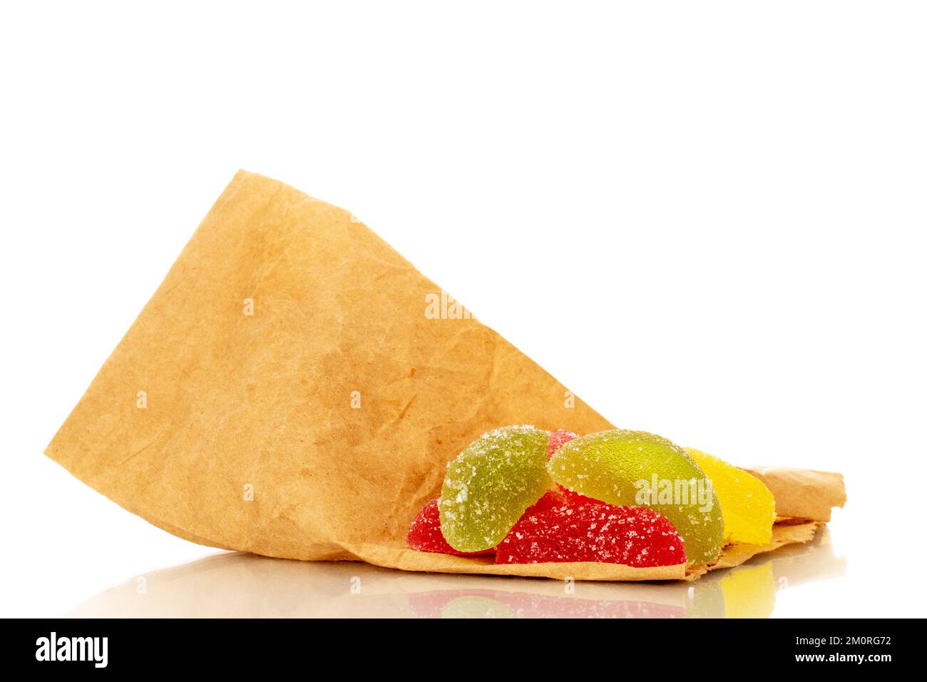 Several sweet marmalade candies on a paper bag, macro, isolated on white background. Stock Photo