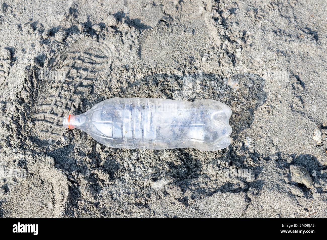 Empty plastic bottle trash laying on a sandy beach. Plastic pollution concept Stock Photo
