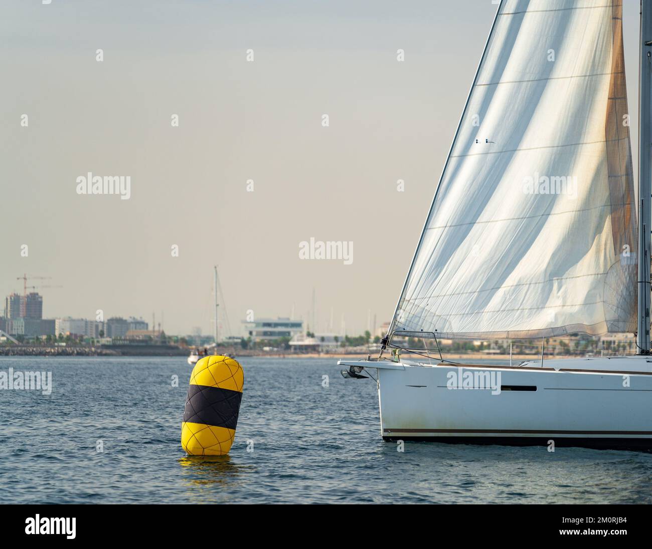 Sailboat bow arriving at buoy against Valencia city Stock Photo