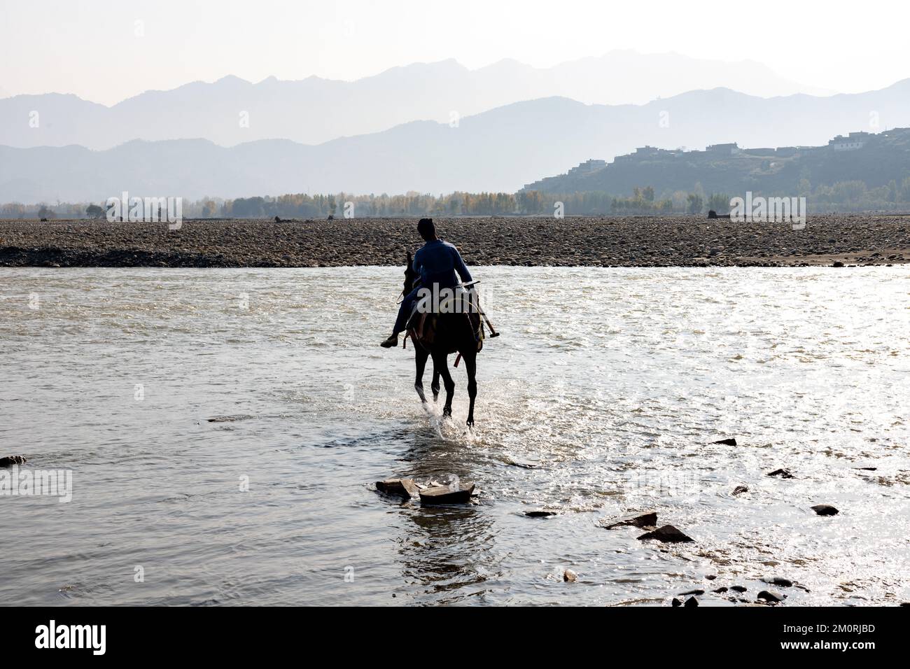 Boy riding horse to cross the river going for work early in the morning