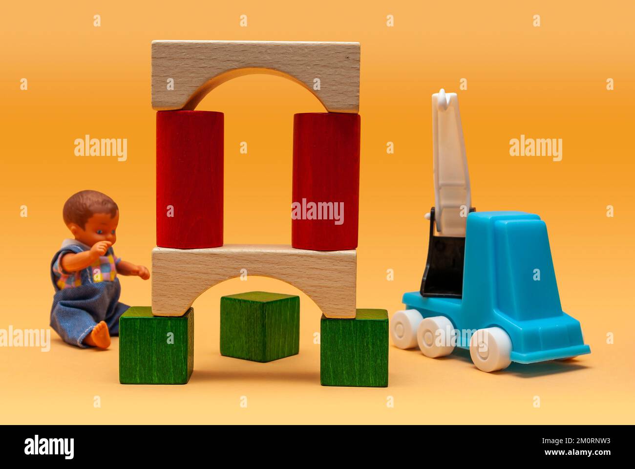Construction of a viaduct by the means of a mobile crane and a boy doll, imitation of such a work site made of colourful building blocks. Stock Photo