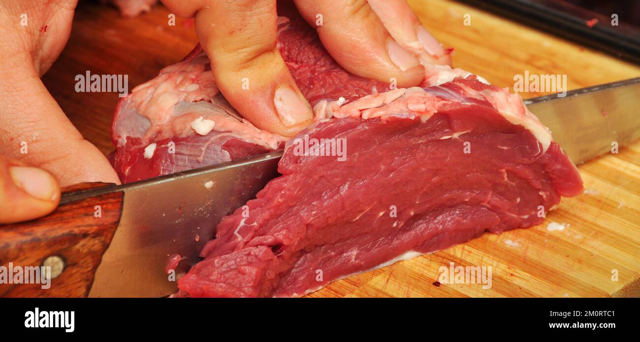 https://c8.alamy.com/comp/2M0RTC1/clean-very-fresh-red-raw-cow-meat-and-a-sharp-knife-on-cutting-board-2M0RTC1.jpg