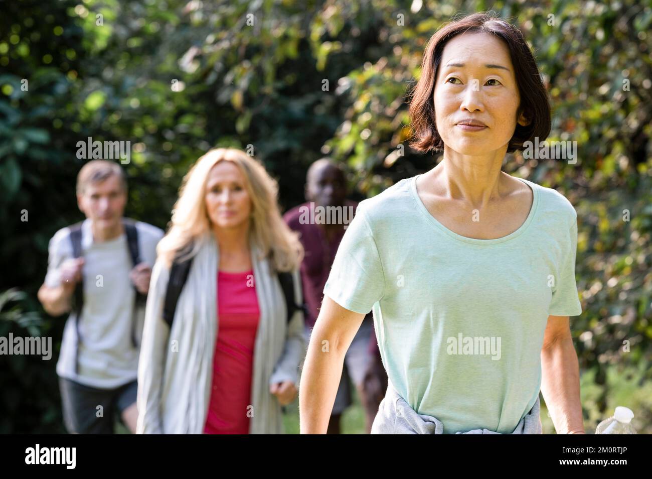 Group of diverse senior friends casually hiking in the woods Stock Photo