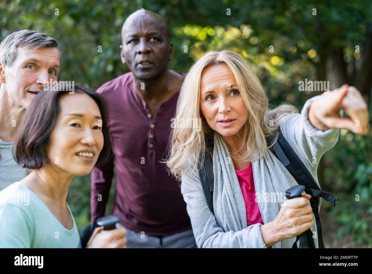 Senior woman giving directions to diverse group of people while pointing Stock Photo