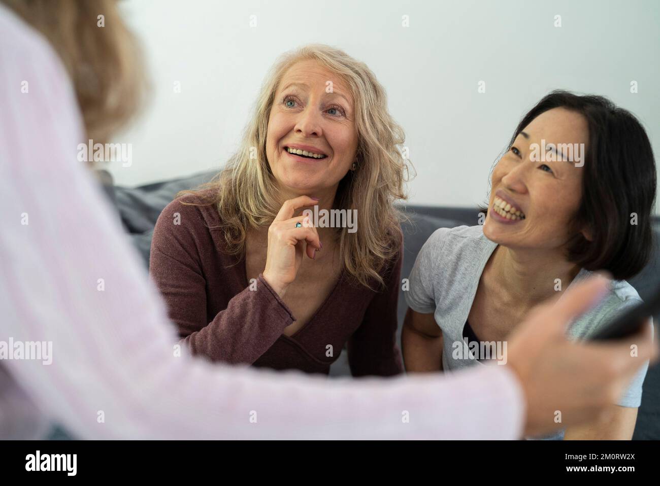 Senior women talking while sitting on sofa at living room Stock Photo