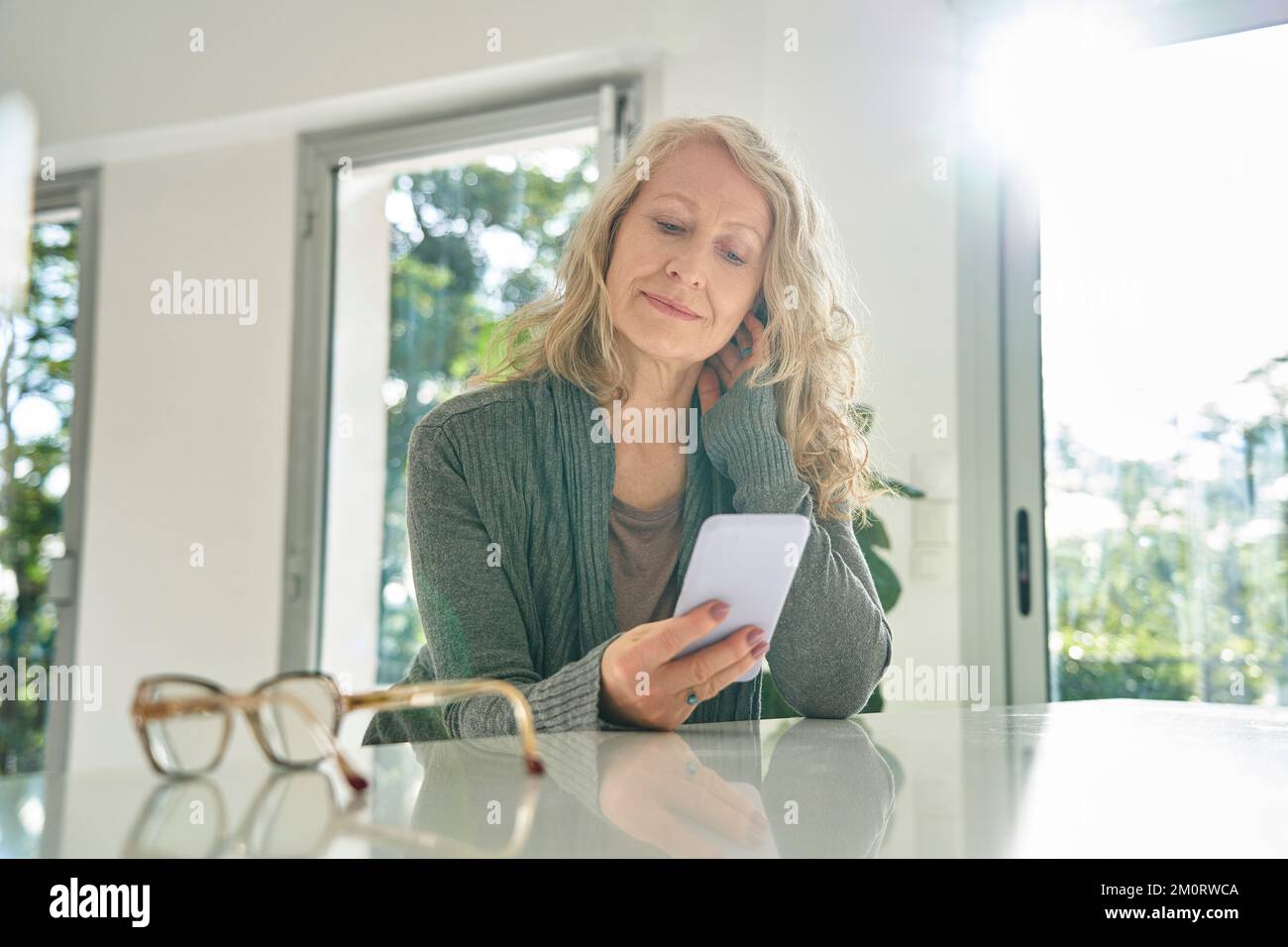 Senior woman using smart phone while sitting at counter Stock Photo