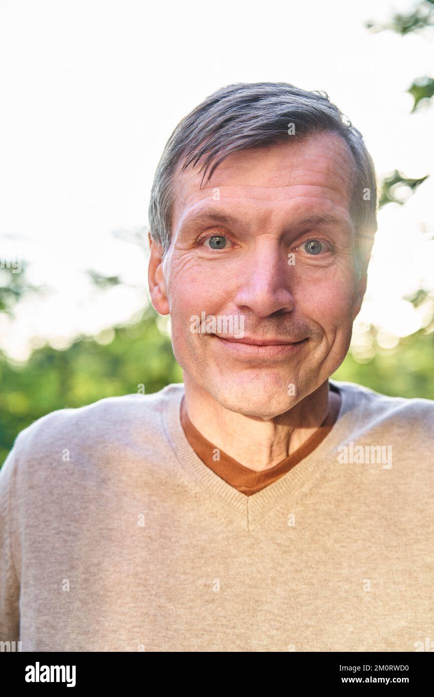 Smiling senior man looking at the camera while standing outdoors Stock Photo
