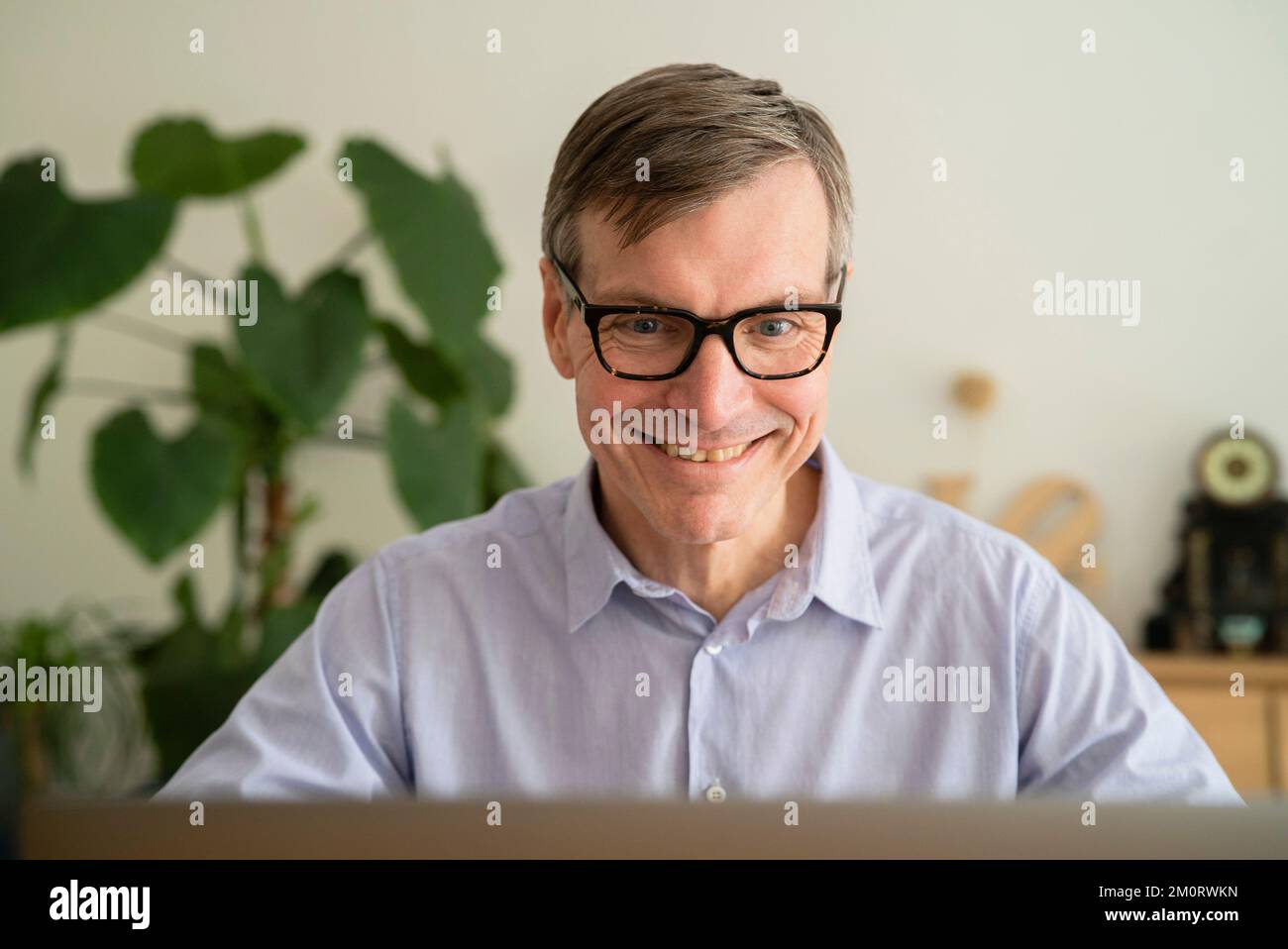 Senior man smiling while using laptop at home Stock Photo