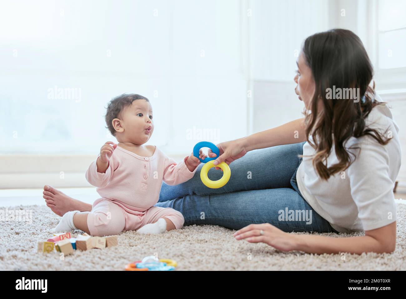 Air kisses for mama. a young mother bonding with her baby while sitting on the floor at home. Stock Photo