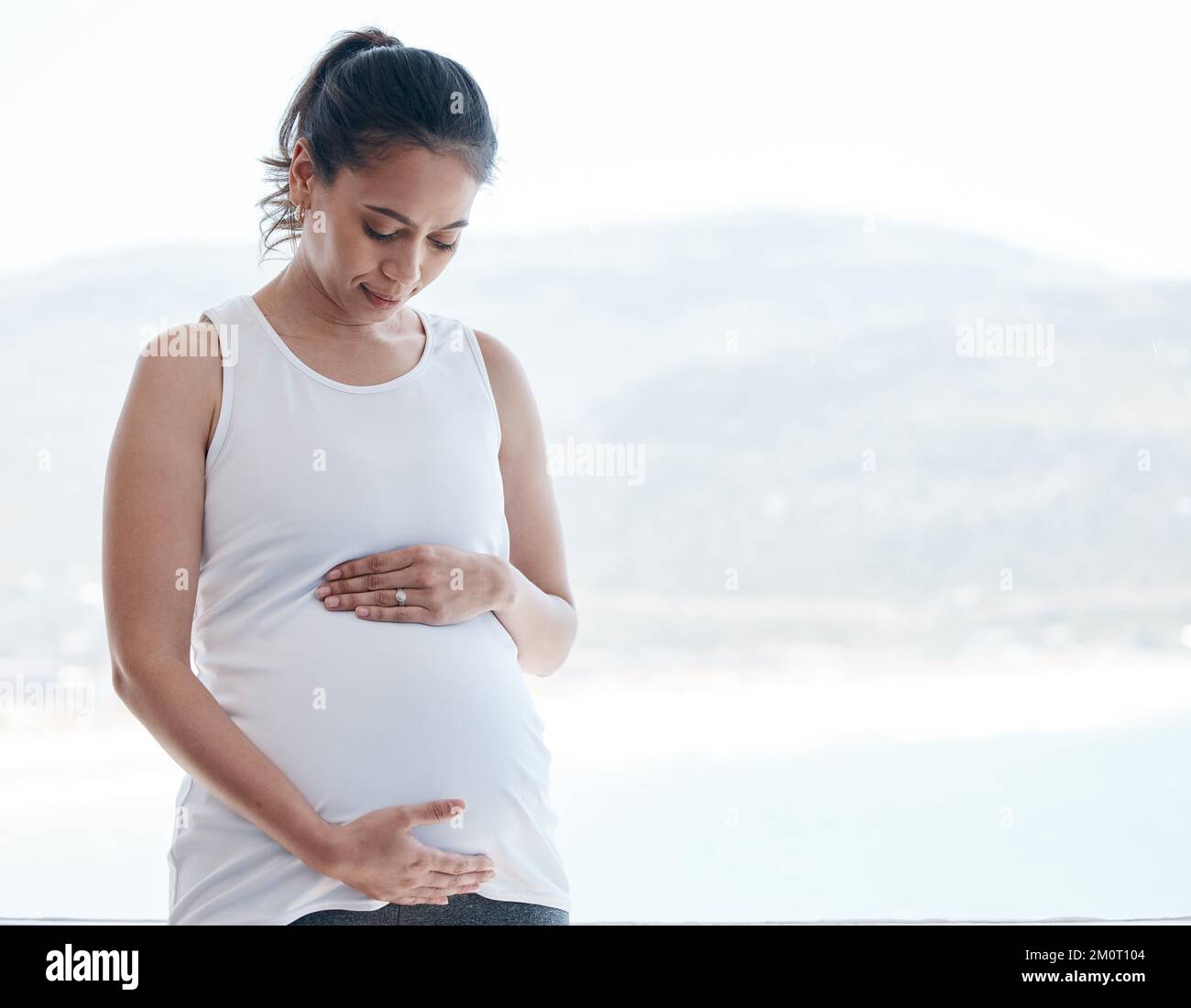 Pregnant hispanic woman touching belly hi-res stock photography