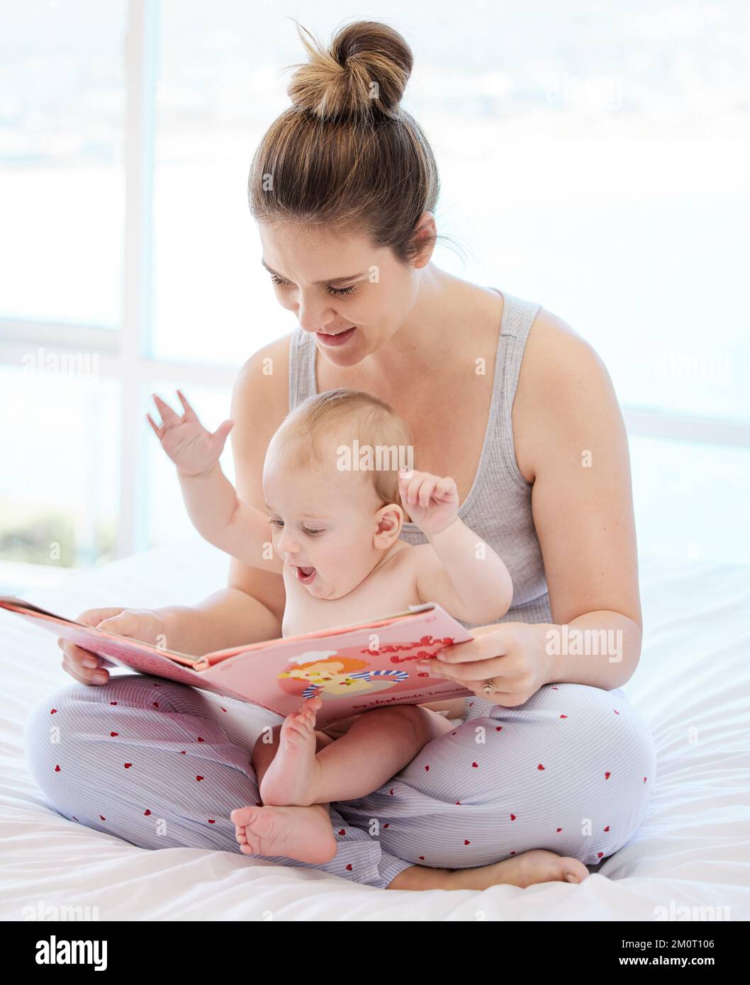 A youthful song of laughter. a young mother bonding with her baby boy while reading a book at home. Stock Photo
