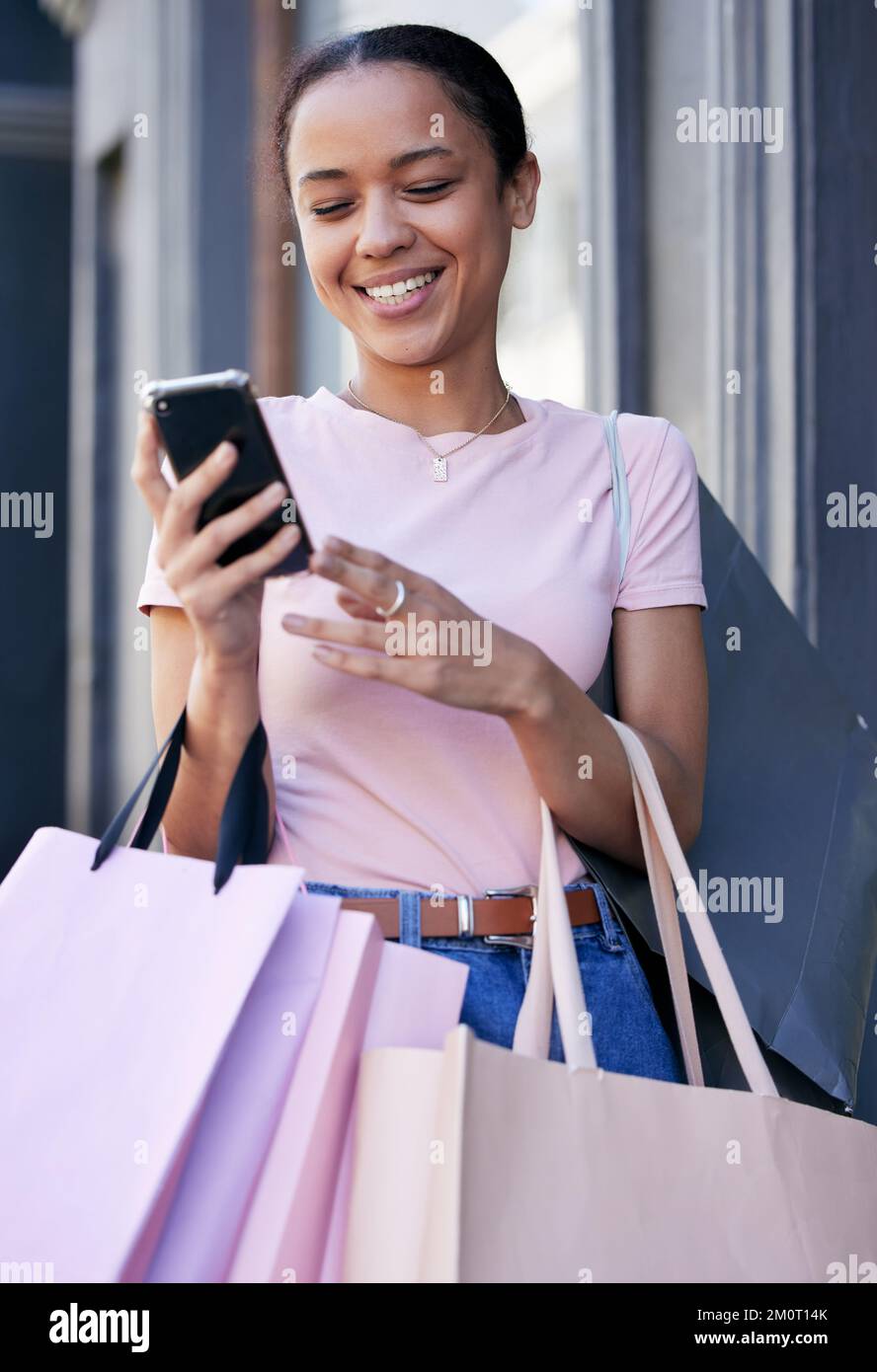Shopping, smartphone and black woman with shopping bag at outdoor mall, retail and fashion boutique with technology and communication. Mobile phone Stock Photo