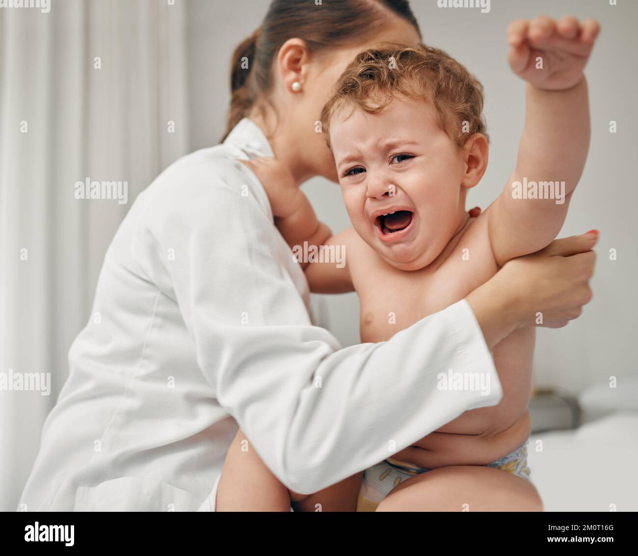 Were almost done. a little baby crying while being examined by a doctor. Stock Photo