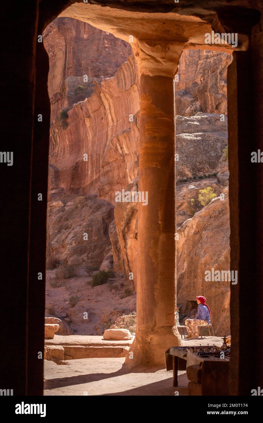 Petra, Jordan - November 3, 2022: Bedouin man and view from Garden Temple to the colorful rocks at Wadi Farasah trail Stock Photo
