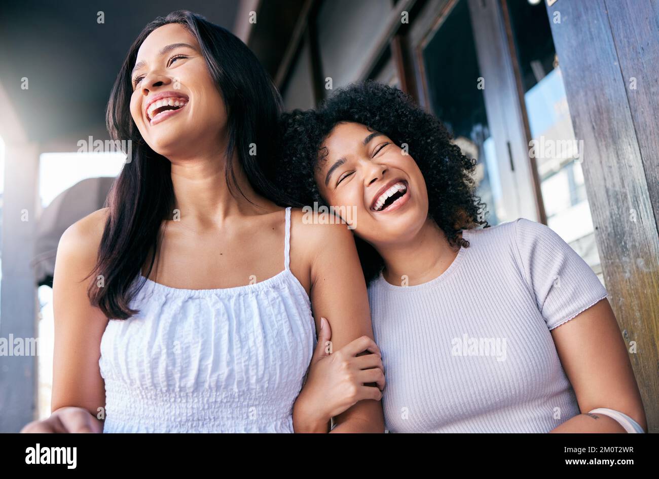 Friends, laughing and women hug in a loving, caring relationship in the city for fun happiness. Black women, walking and travel in an urban town with Stock Photo