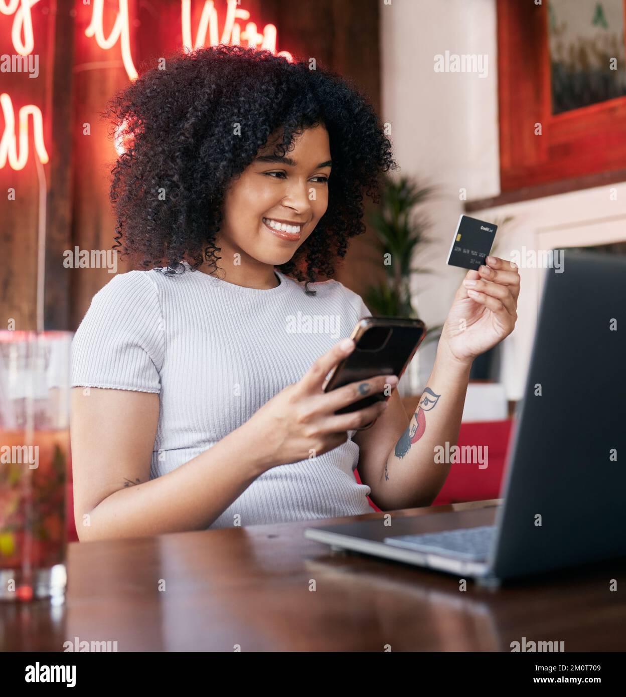 Credit card, phone and woman on laptop in cafe online shopping, ecommerce website payment for fashion sale. Black woman, retail customer and Stock Photo
