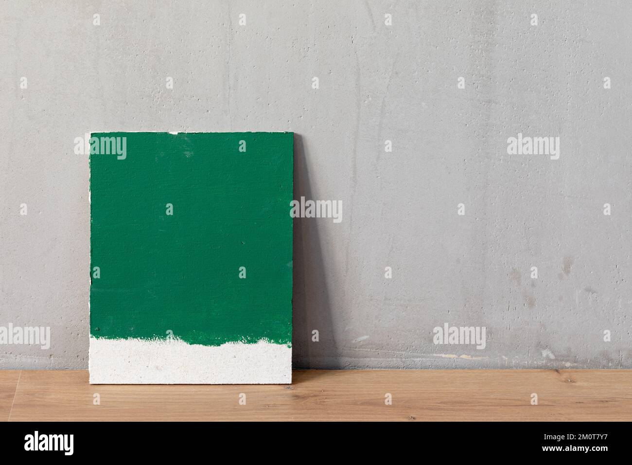 Green color sampler at blank gypsum plaster wall. Choosing wall paint color during house renovation. Stock Photo