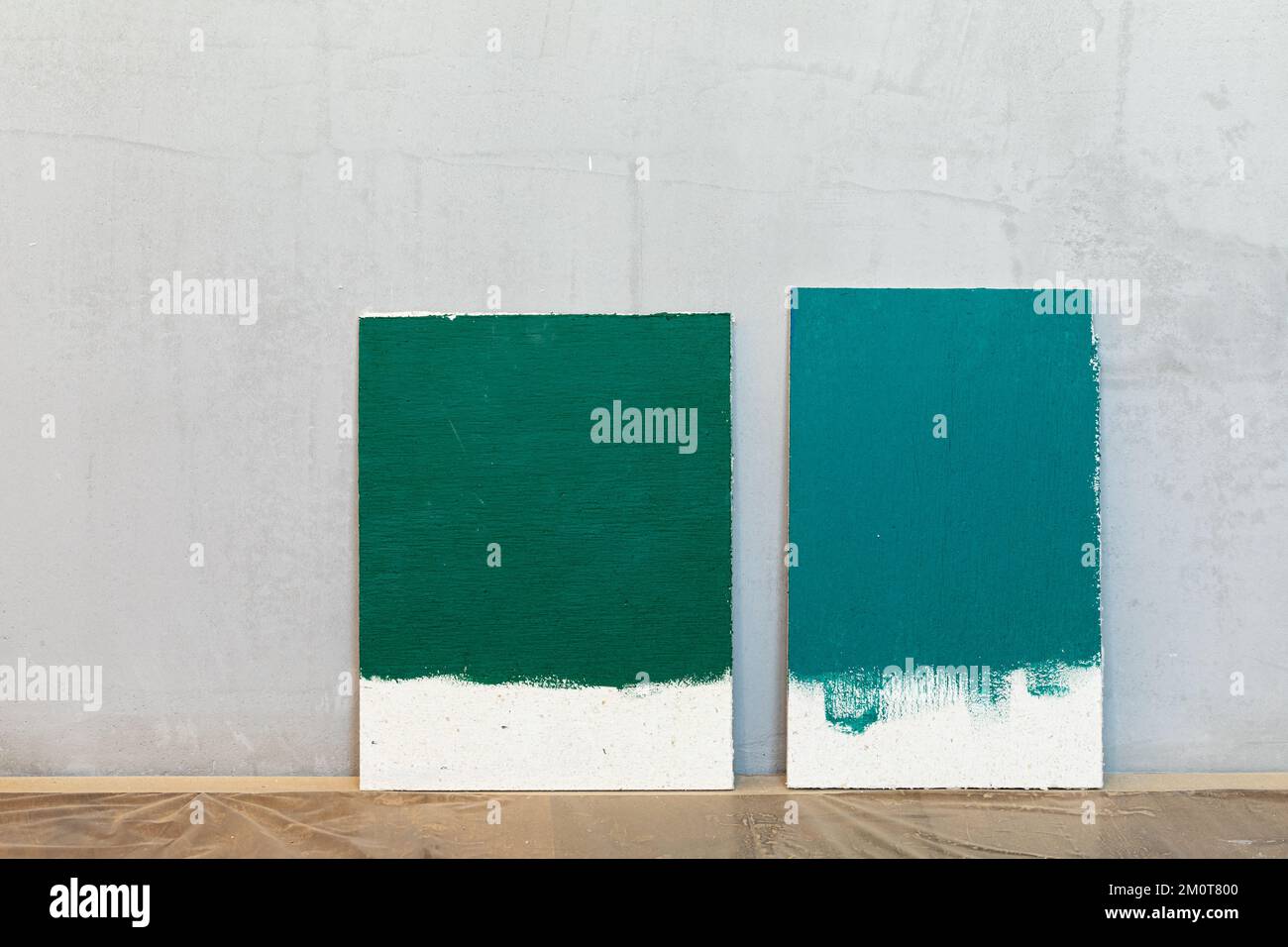 Green color samplers at blank gypsum plaster wall. Choosing wall paint color during house renovation. Stock Photo