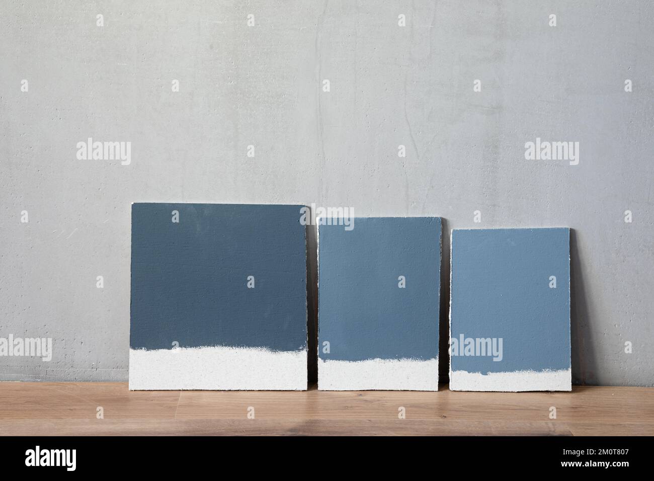 Grey color samplers at blank gypsum plaster wall. Choosing wall paint color during house renovation. Stock Photo