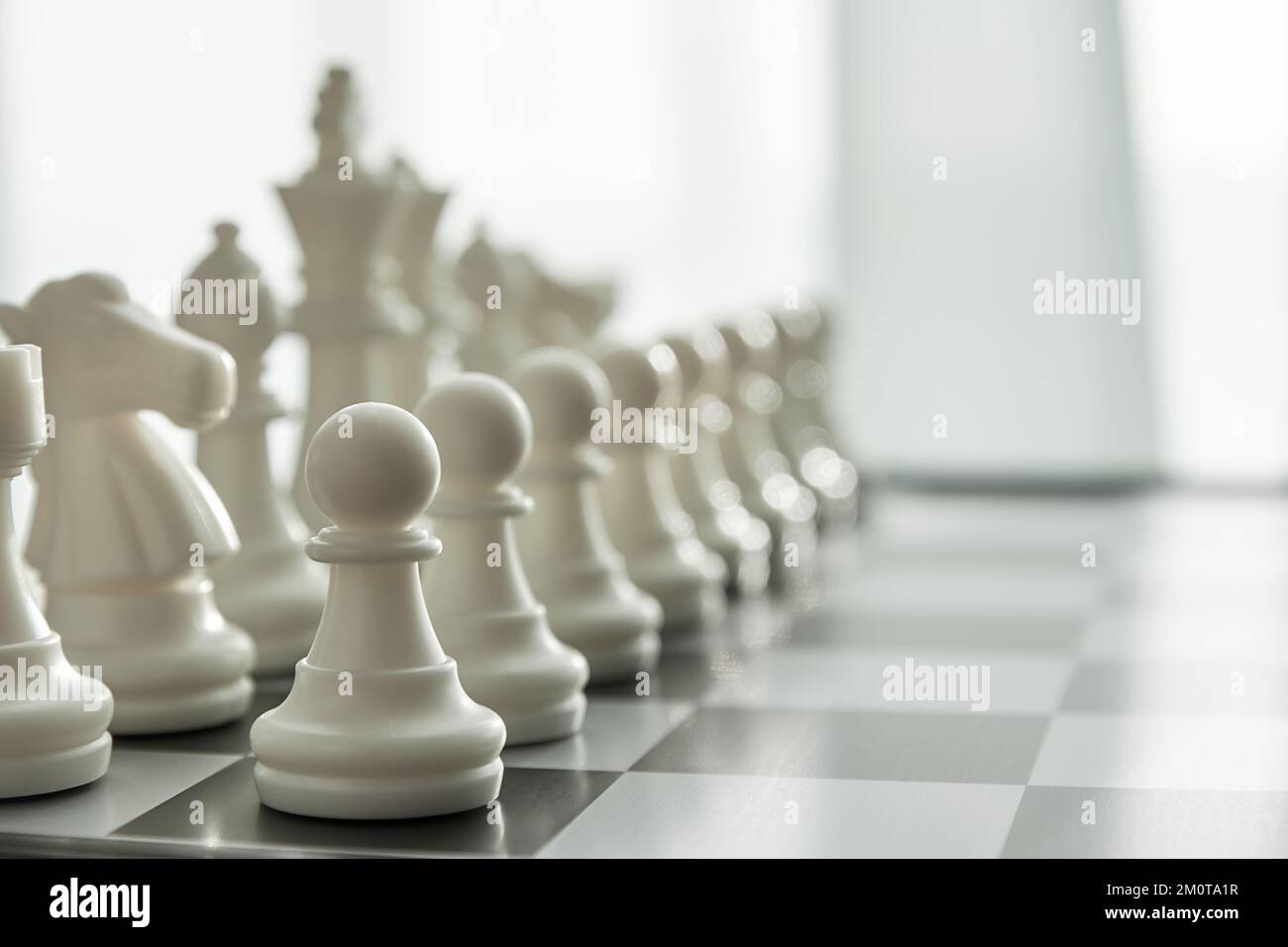 White Chess figures in a row on the board with blurred perspective view. Intellectual games and leisure activity concept Stock Photo