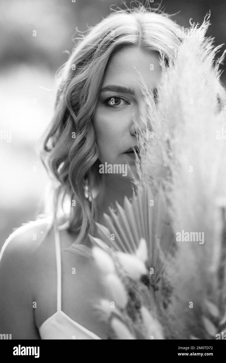happy bride girl in a white light dress with a bouquet of dried flowers ...