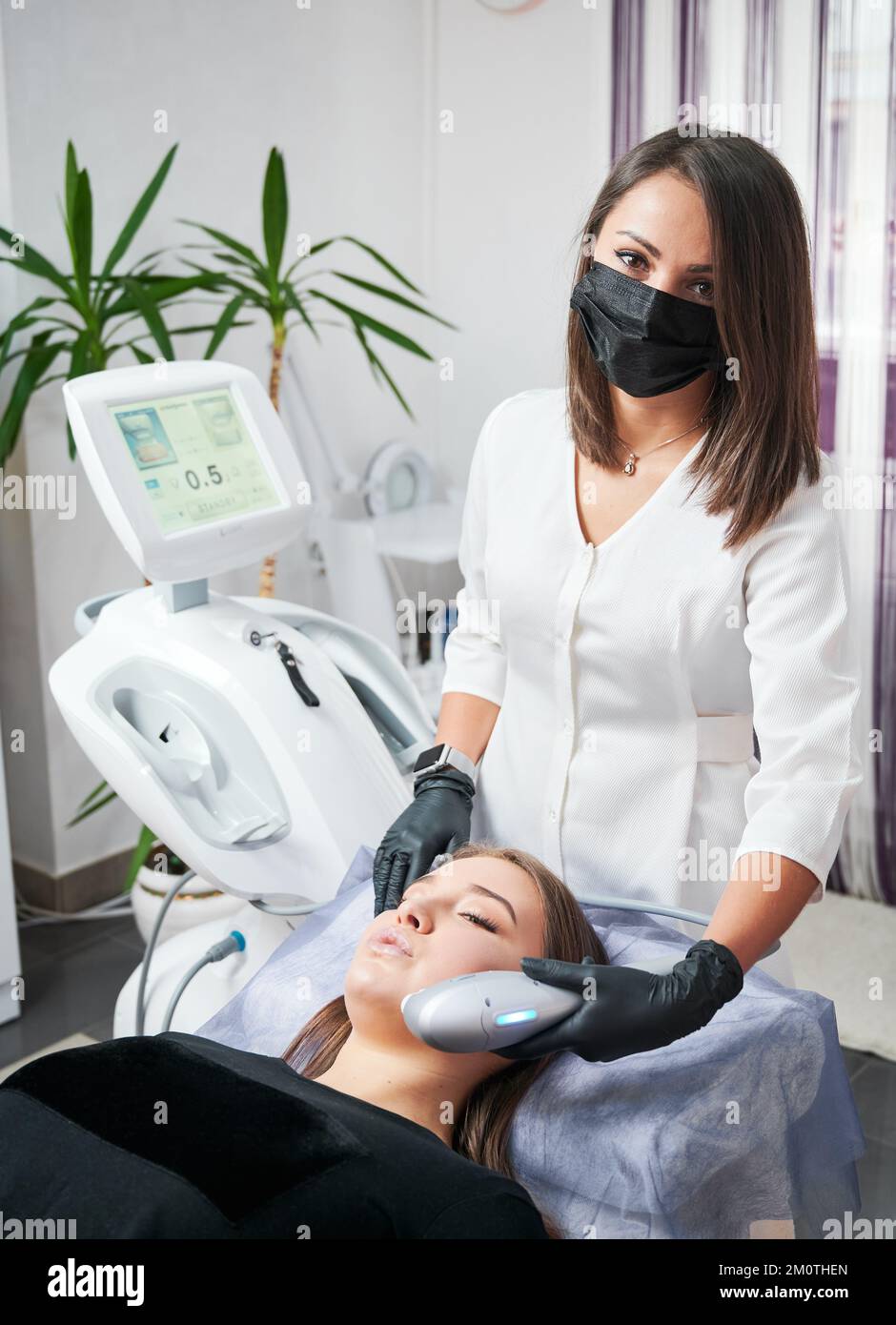 Kyiv, Ukraine - December 26, 2020: Specialist in the field of aesthetic medicine performing ultrasonic non-surgical facelift procedure for woman. SMAS lifting - great alternative to plastic surgery. Stock Photo