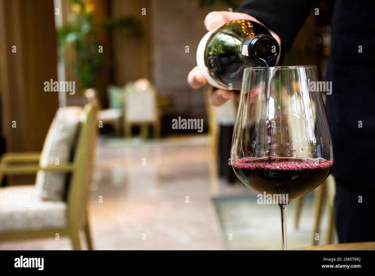 Thai restaurant manager and waiter pouring wine into glass for served
