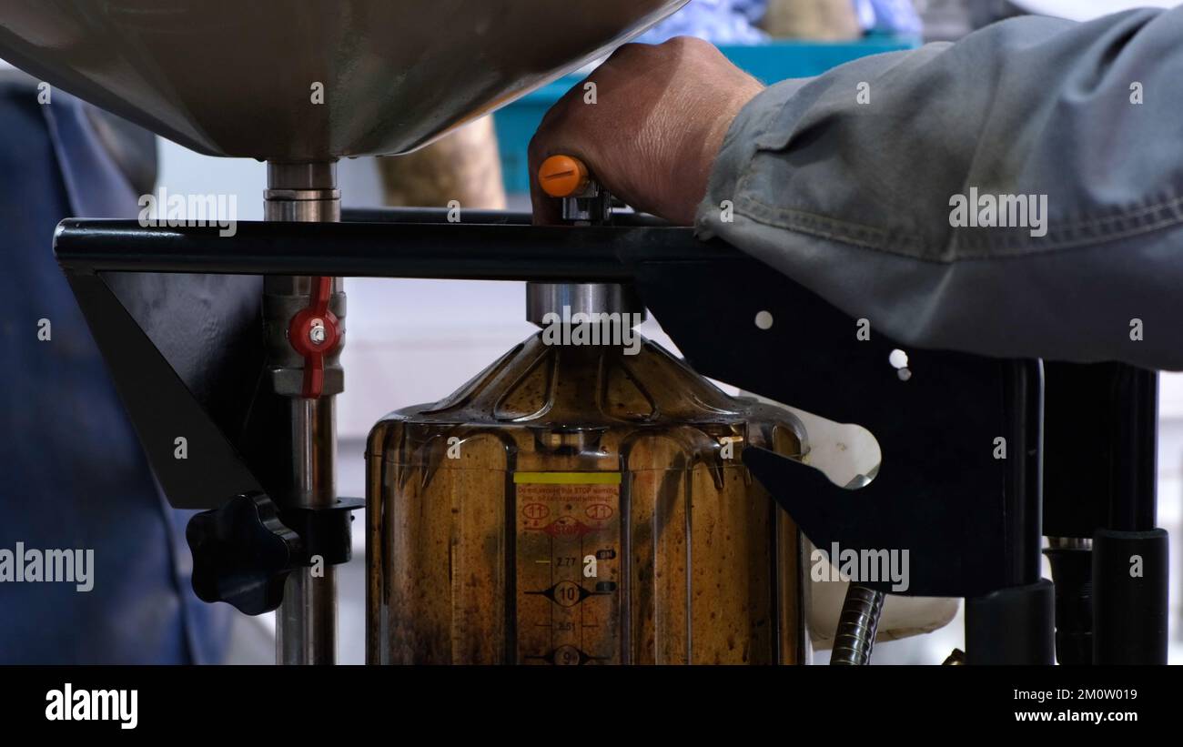 Change engine oil. The male hands of a mechanic drain the old oil from