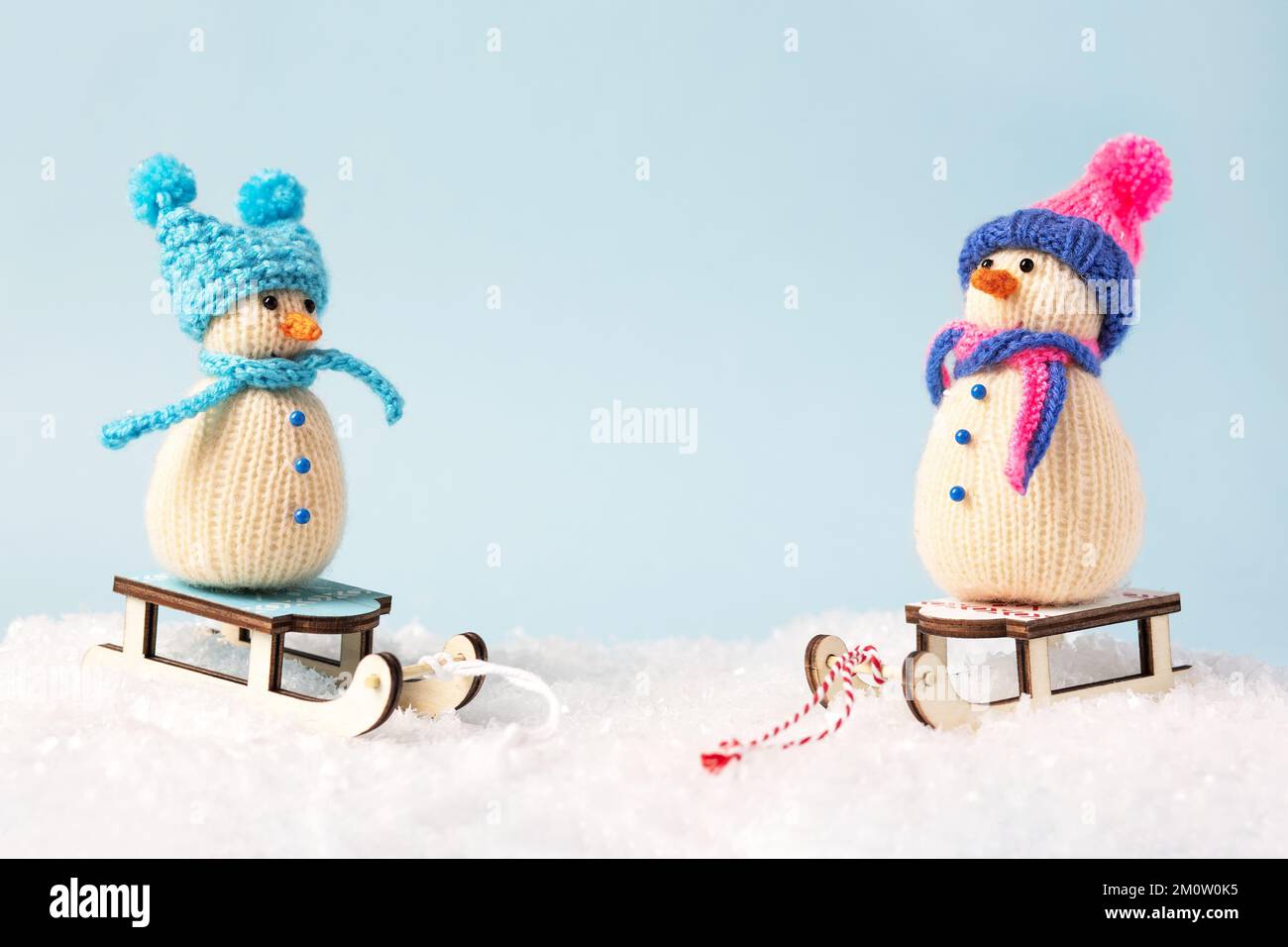 Two knitted snowmen in blue and pink knitted hats and scarves. Merry Christmas and New Year 2023 greeting card Stock Photo