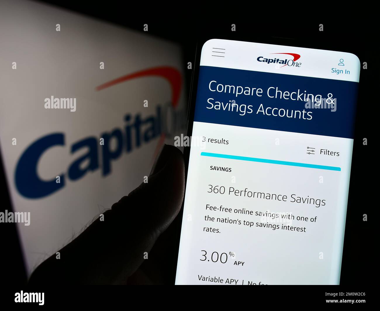 Person holding cellphone with website of US company Capital One Financial Corporation on screen with logo. Focus on center of phone display. Stock Photo