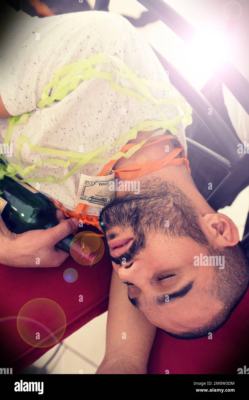 Party, drunk and alcohol with a man sleeping on the floor after a new year celebration or event closeup. Beer, social and tired with a male asleep in Stock Photo