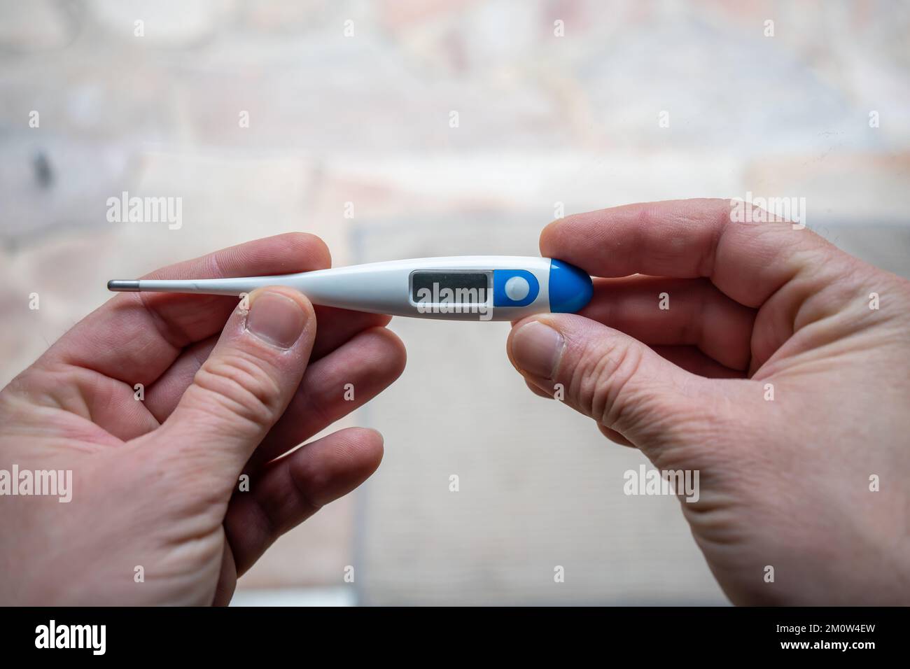 Illness. Home treatment. Flu and cold. A man takes his temperature with a thermometer Stock Photo