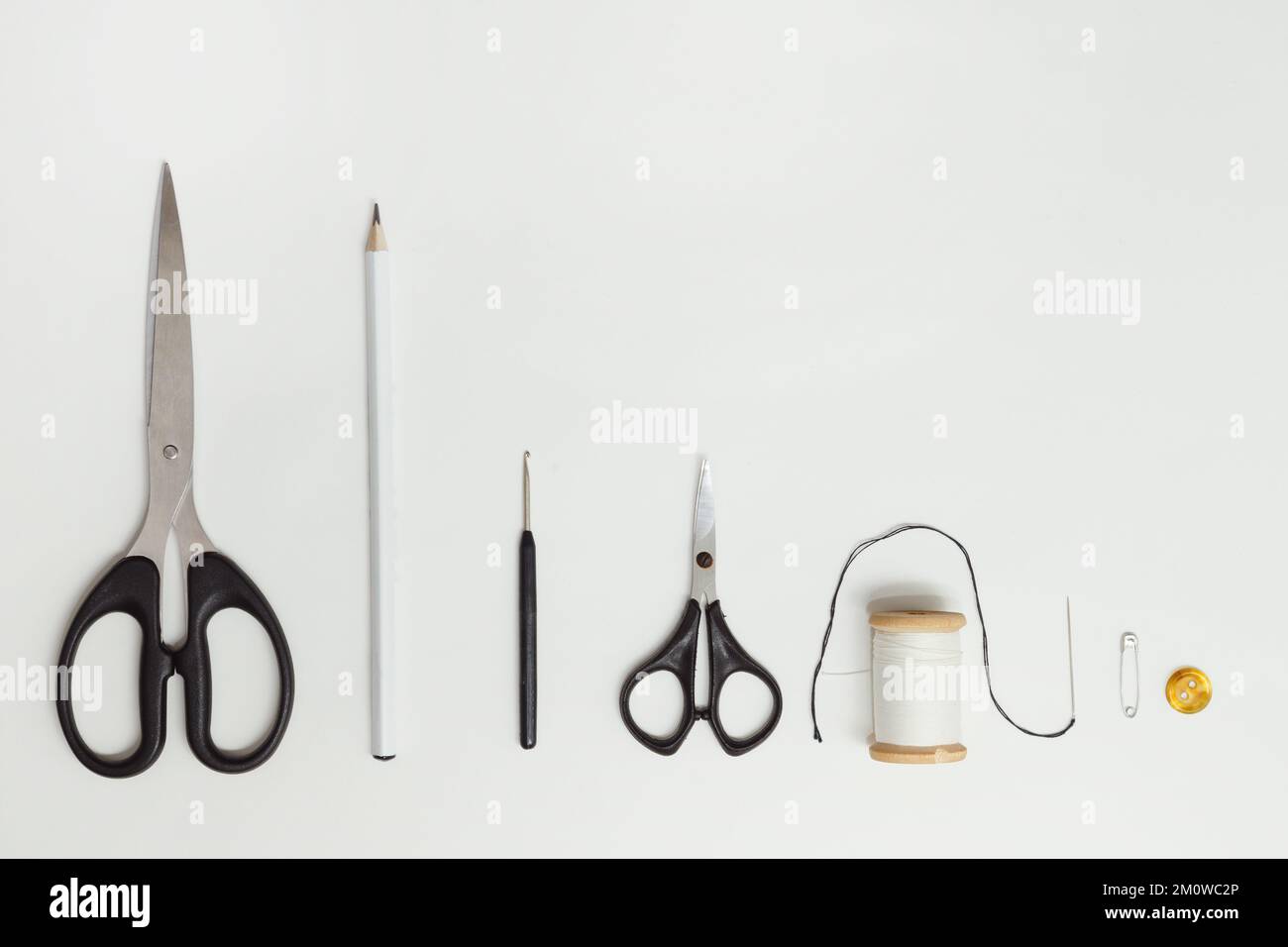 Scissors and sewing supplies on white desk. Sewing and knitting tools on white background, needlework concept. Top view on white Stock Photo