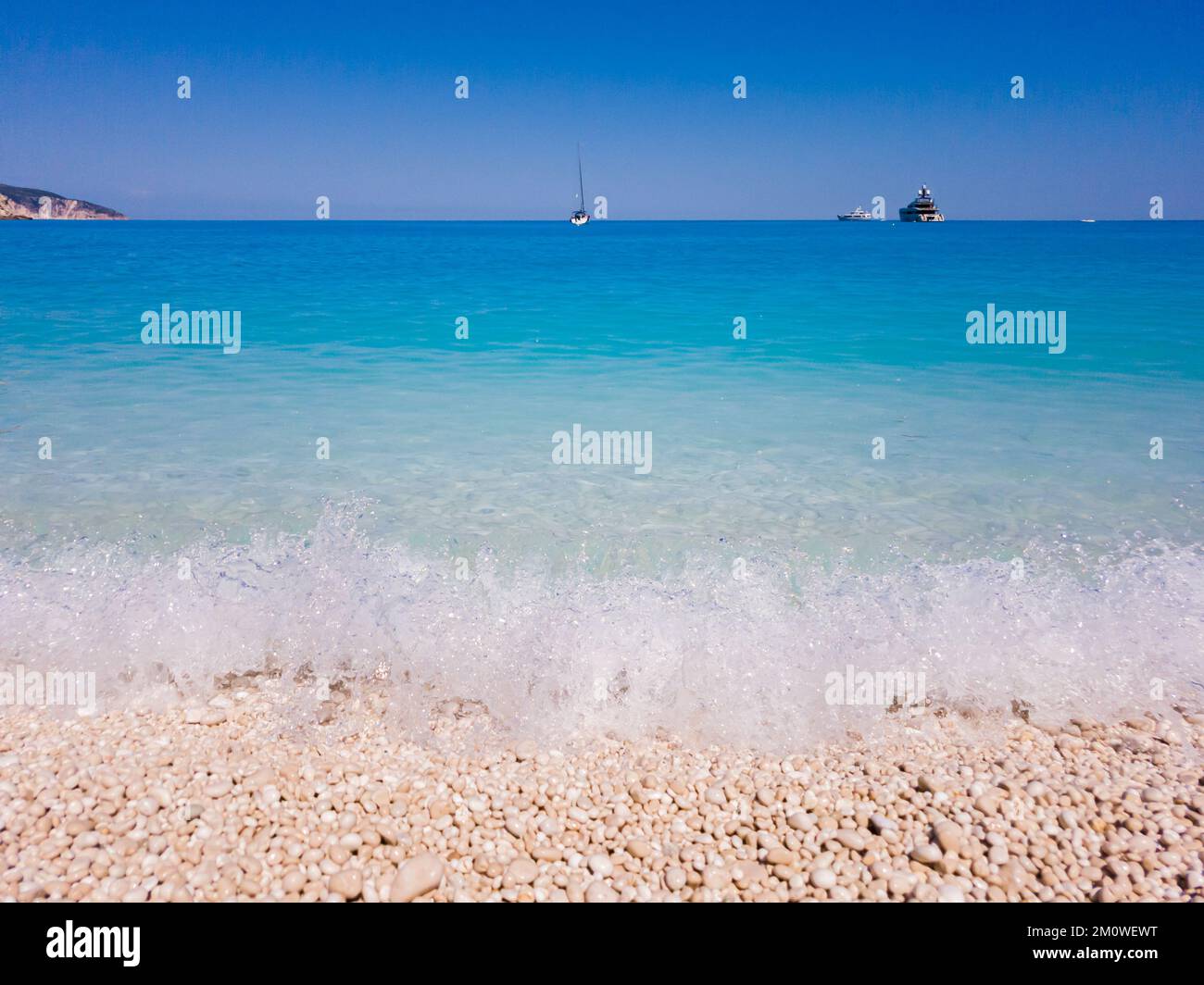 Surf from beach in Myrtos. Turquoise and blue Ionian Sea water. Summer scenery of famous and extremely popular travel destination in Cephalonia, Greece, Europe. Stock Photo