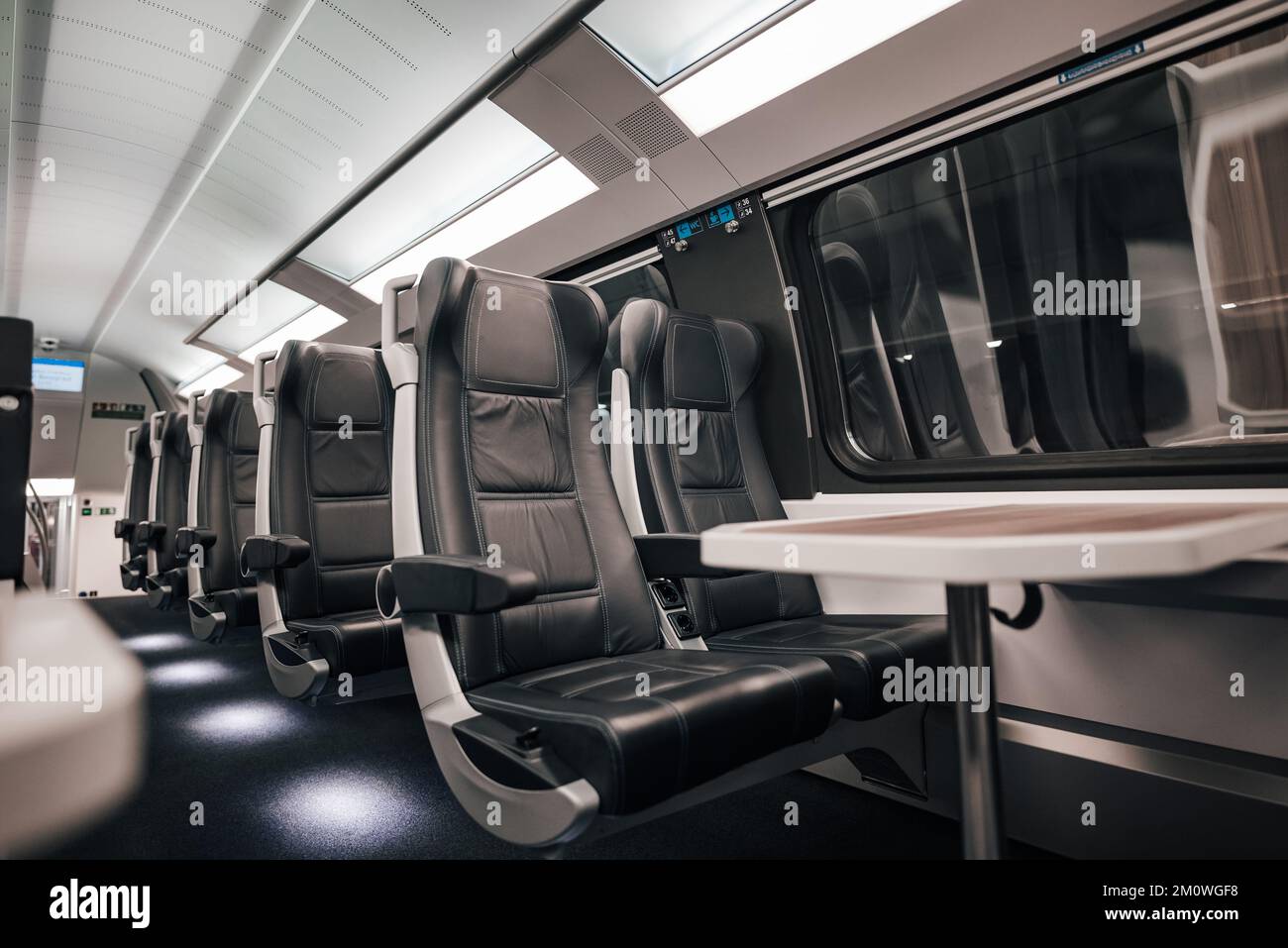 Table and comfortable leather seats by window in railroad car. Interior of modern passenger